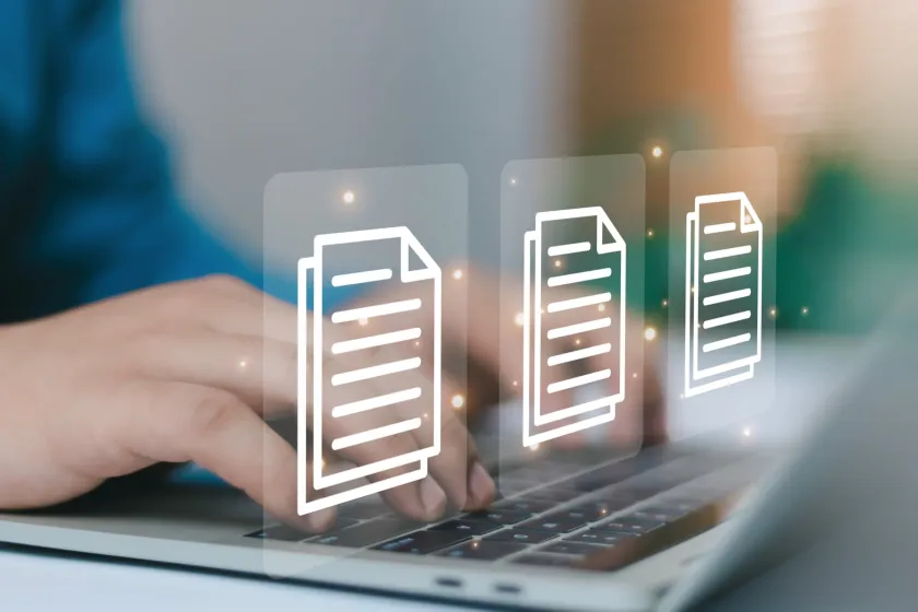 Hands typing on a laptop with three glowing digital document icons overlaid